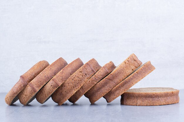 Black bread slices lined up on marble surface