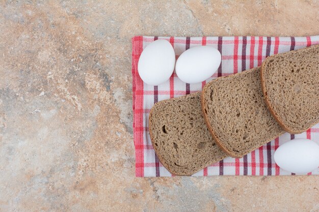 Black bread slices on tablecloth with eggs