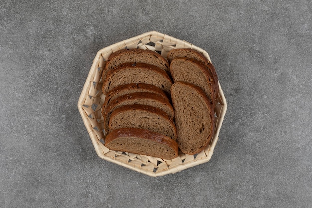 Black bread slices in wooden basket.