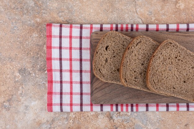 テーブルクロスと木の板の上の黒いパンのスライス