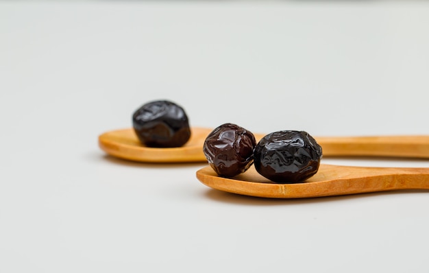 Black and brown olives in wood spoons on white. side view.