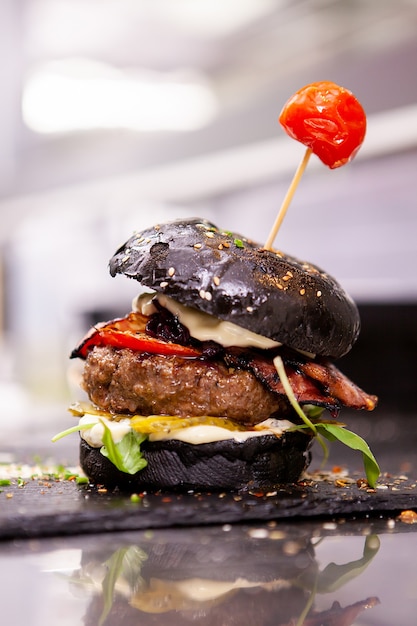Black burger on stone cutting board in kitchen restaurant