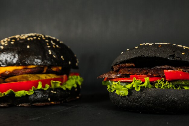 Black burgers beef lettuce tomato cucumber cheese side view