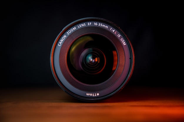 Black camera lens on brown wooden table