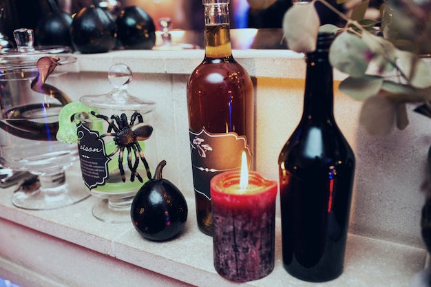 Black candles stnad among bottles with wine