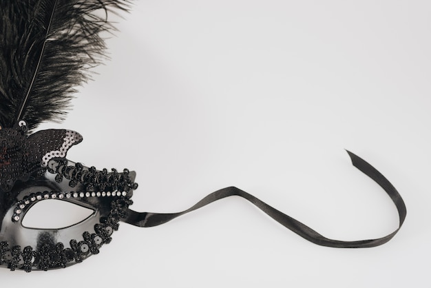 Black carnival mask with feather on light table