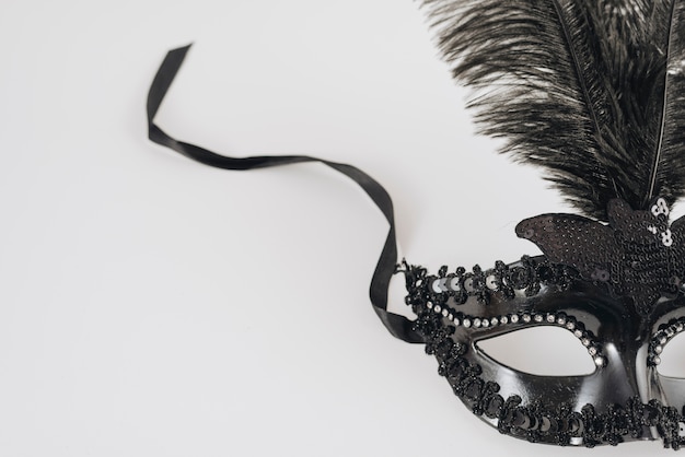 Black carnival mask with feather on table