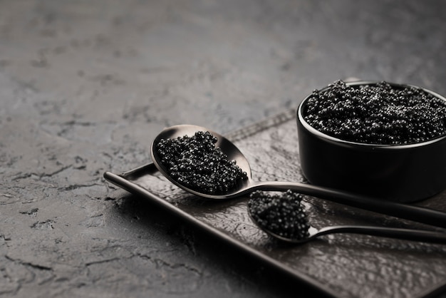 Black caviar in bowl with spoons and ladle
