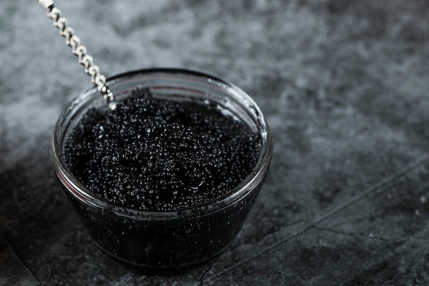 Black caviar in a small jar with a spoon inside