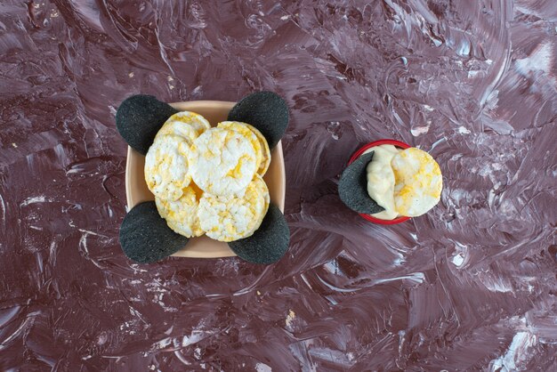 Foto gratuita patatine nere, patatine al formaggio e yogurt in una ciotola, sul tavolo di marmo.