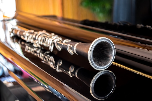 Free photo black clarinet lying on closing grand piano