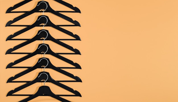 Black clothes hangers on terracotta background with copy space. Idea for sale, creative shopping concept. Flat lay, minimalistic style. Creative layout. Fashion, shop sale. Blog banner