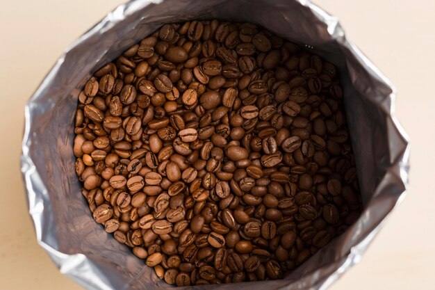 ベージュ色の背景に黒いコーヒー豆