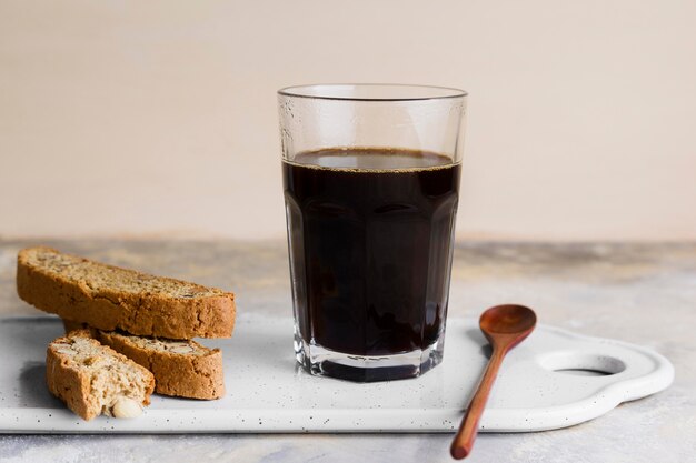 Black coffee next to bread with seeds