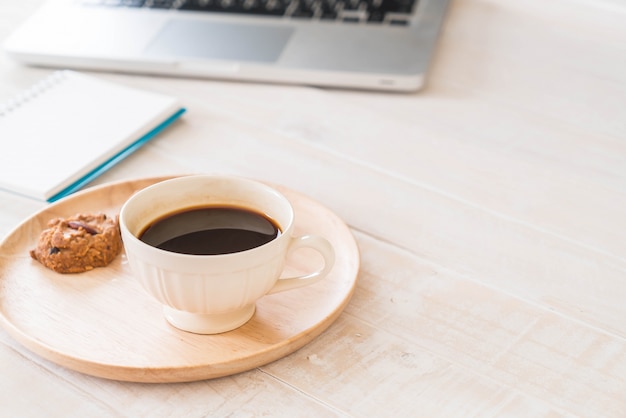 Caffè nero e biscotti con il computer portatile e il taccuino