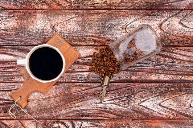 black coffee on wood board with jar of coffee beans top view