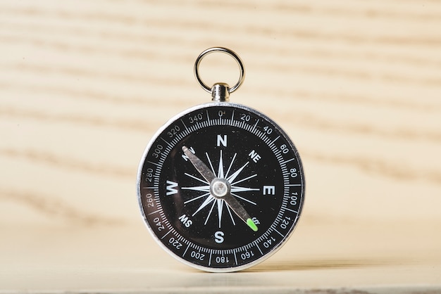 Black compass on wooden surface