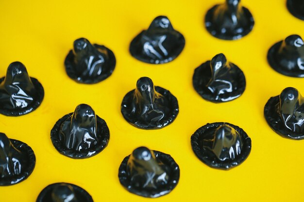 Black condoms isolated on yellow surface