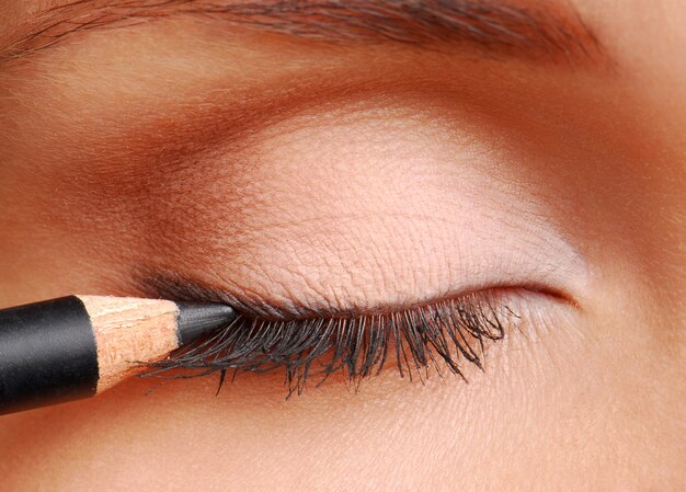 Black cosmetic pencil. Women eyes closed. Long eyelashes.