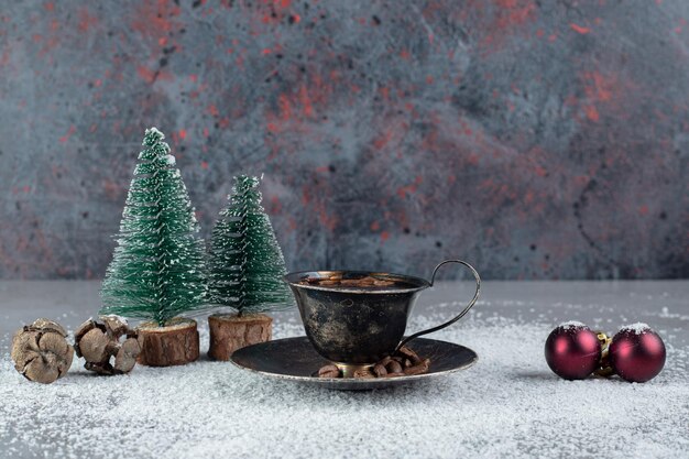 Black cup of coffee with christmas decorations on coconut powder on marble surface