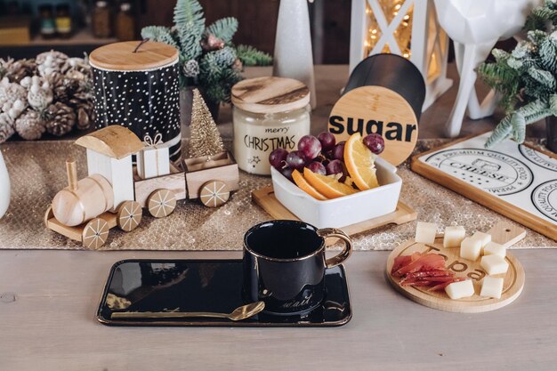 Black cup, food and New Year decorations are on the table in the room. New Year eve concept