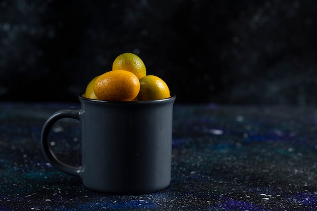 Free photo black cup full with organic kumquats