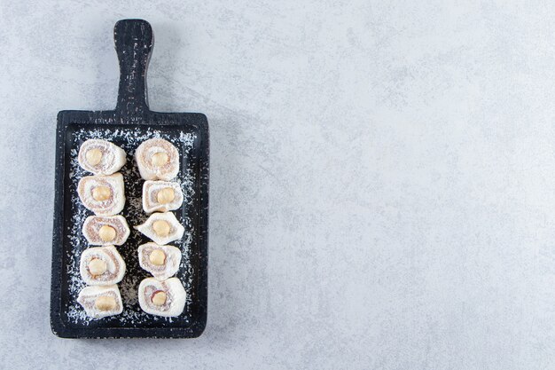 Black cutting board of delicious treats with nuts on stone background.