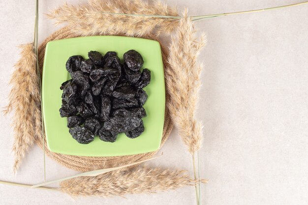 black dry plums in a ceramic plate on concrete.
