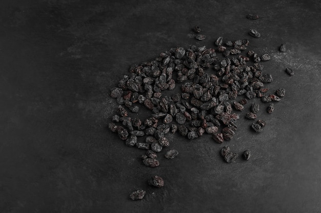 Black dry sultanas on black background.