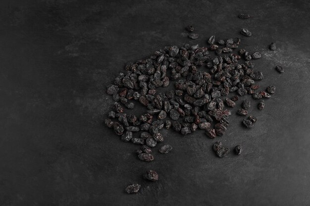 Black dry sultanas on black background.