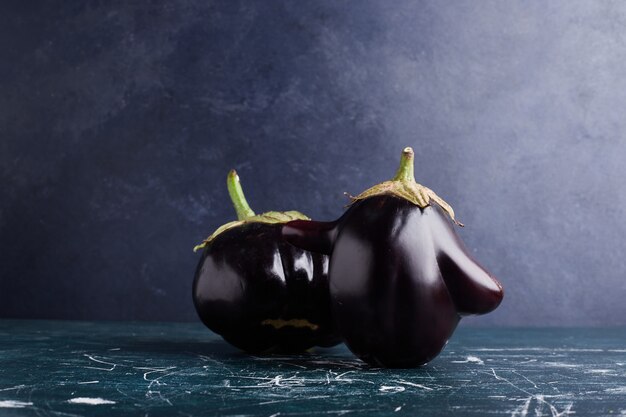 Black eggplants isolated on blue table.