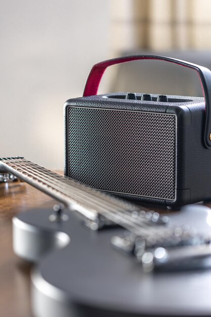 Black electric guitar and speaker on a wooden table