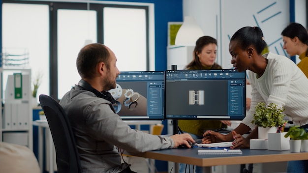 Black employee and project manager analysing mechanical metalic parts