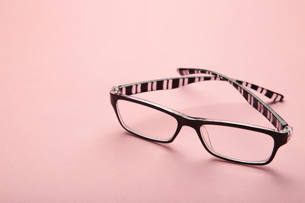 ピンク​の​背景​に​視覚​障害​の​ある​人​に​日常​生活​を​読む​ため​の​黒い​フレーム​の​黒い​眼鏡​眼鏡