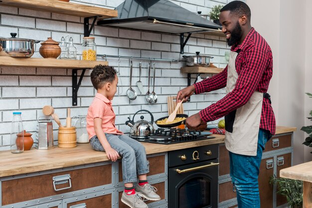 黒人の父と息子が台所で料理をする