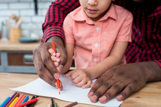 Black father and son drawing on paper