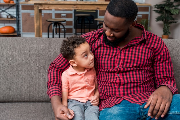 Black father and son talking on couch 