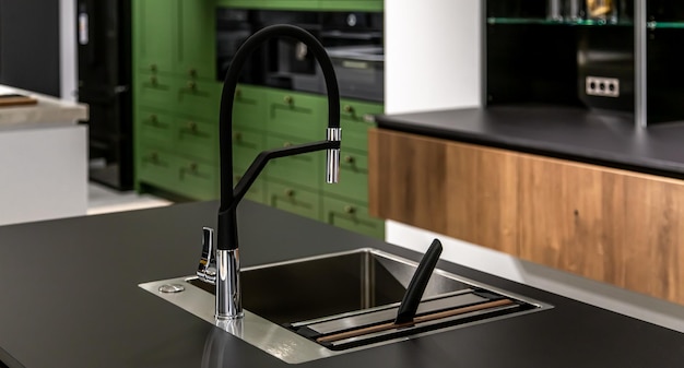 Black faucet with a steel sink in a stylish modern kitchen