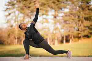 Free photo black female athlete warming up before ports training and doing stretching exercises in the park