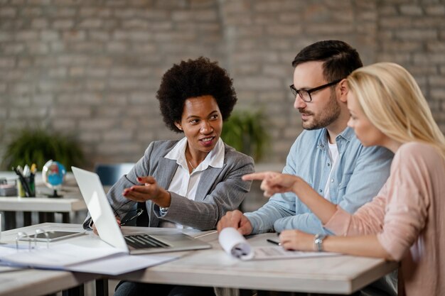 Black female insurance agent using computer with a couple during consultations in the office