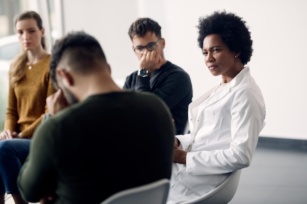 Free photo black female psychotherapist talking to members of group therapy at medical center