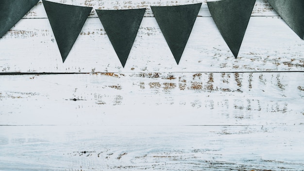 Black flags in Halloween style hanging on painted wooden background