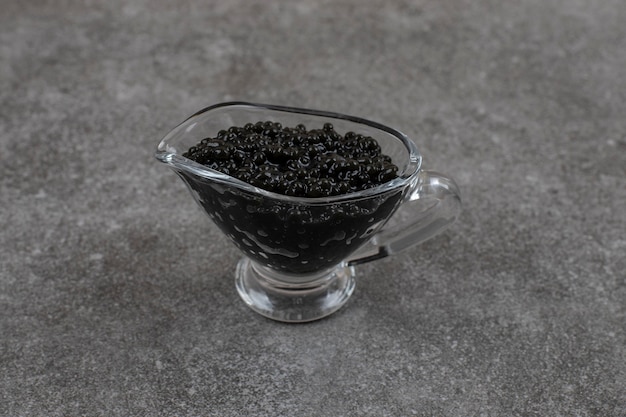 Free photo black fresh caviar in glass bowl on grey surface