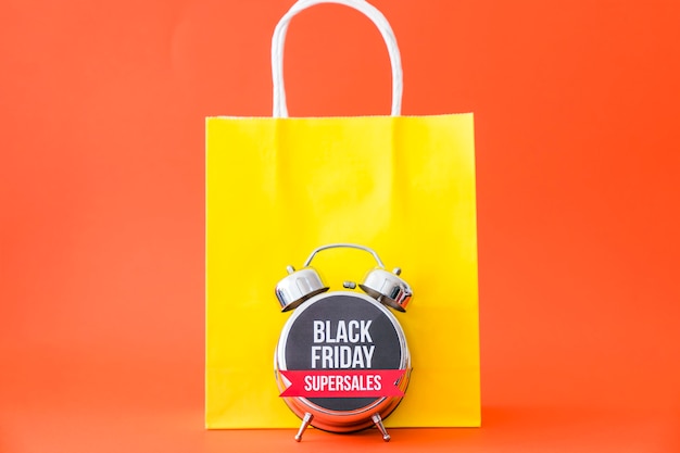 Free photo black friday concept with alarm clock in front of bag