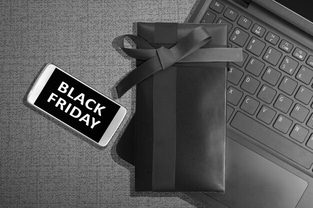 black friday message on the mobile phone screen with gift box on black background. black friday concept