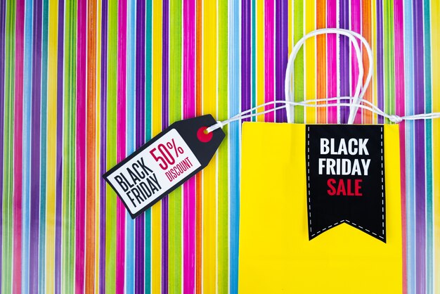 Black friday shopping bag with tag on colorful background