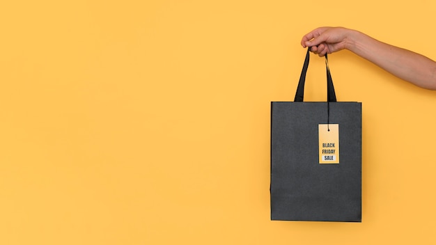 Black friday shopping bag on yellow copy space background