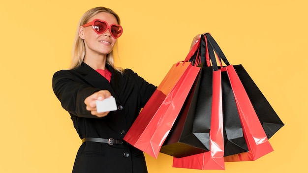 Black friday shopping woman showing bags and voucher