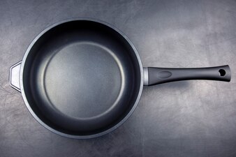 Black frying pan with non-stick teflon coating on black Premium Photo