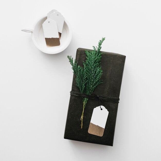 Black gift box with cypress branch on light table